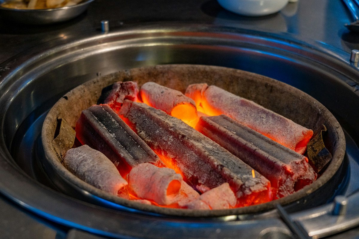 Sticks of charcoal glowing orange inside a tabletop grill